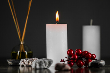 Burning aromatic candle and plants on table.
