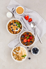 Served table, healthy breakfast. granola bowls with berry, banana and peanut paste and yogurt on grey background. Top view - 441646735