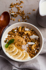 Smoothie bowl with banana, granola and coconut on a table, closeup view. Healthy vegan detox smoothie bowl, superfood - 441646780
