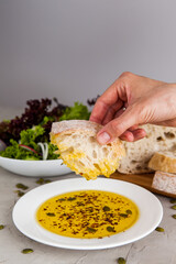 Woman hand dipping bread into olive oil. Cooking concept - 441646951
