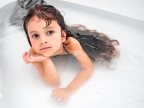 Girl with long hair lying in the water in the bathtub