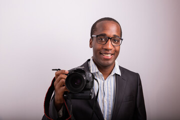 Smiling African photographer elegantly dressed with camera in hand. Model isolated on white background.