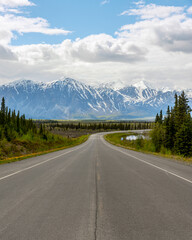 Fototapeta na wymiar Haines Highway, Yukon Territory with huge snow capped peaks and clouds with blue sky. 