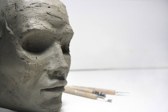 Clay face, sculpture modeling and tools on white background