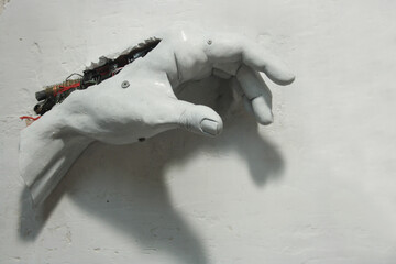 Cybernetic clay hand and electronic recycling materials. Sculpture on white plaster background....