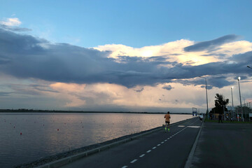 Asphalt road for jogging near lake, mans' silhouete running, early morning, sunrise, perfecr time and place for running.