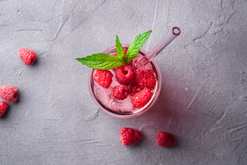 Fresh ice cold berry juice drink with mint, summer raspberry lemonade in glass with straws on stone...