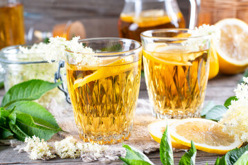 Elderflower syrup with lemon on table. With elderflowers. Natural light, selective focus.