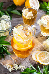 Jug of elderflower syrup and elderberry flowers on table