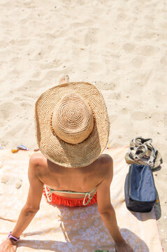 Summer Holiday Fashion Concept - Tanning Woman Wearing Sun Hat At The Beach On A White Sand Shot From Above