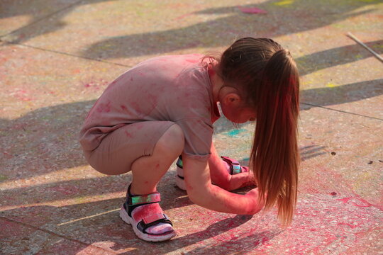 A child draws with chalk on the asphalt.Little girl stained with paint hands feet clothes
