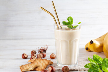 Photo of fresh Made Banana Smoothie on a table with cookies and banana. Milkshake. Protein diet. Healthy food concept, space for text.