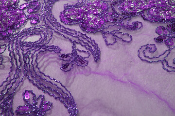 Detail of the transparent fabric with floral motifs, purple: decorated with intricate embroidery.