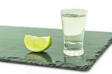 Shot glass with tequila and lime on a white background