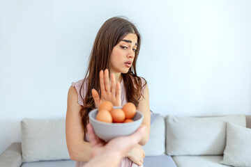 Selective focus of a beautiful young women  refusing to eat eggs.  Young beautiful woman holding...