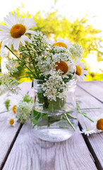 A bouquet of daisies in a glass vase. White daisies in a jar close-up. Beautiful wildflowers sunny flowers on a wooden background.