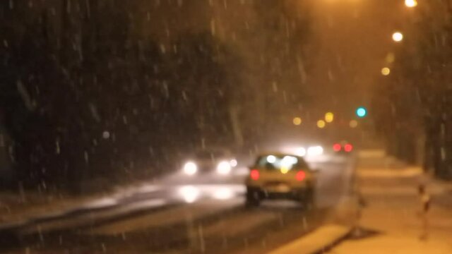 
Borroso nocturno de tr&aacute;fico de coches con luces y la nieve cayendo
