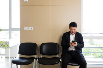 Male asian businessman got good news, rejoices in the waiting room for an interview, near the...