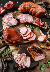 Assortment of cold meats products, ham, sausage, salami, parma, prosciutto, bacon on wooden cutting...