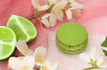 green macaroon cake on a pink background with a slice of lime. Lime macaroon with green cream. Round mint dessert. High quality photo