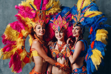 Three Women dancers in brazilian samba carnival costume with colorful feathers plumage.