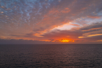 Calm sea with sunset sky and sun through the clouds over. Ocean and sky background, seascape.
