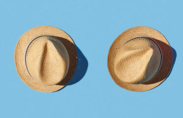 Straw hat with ribbon on pink pastel background, top view