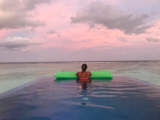 Woman floating in infinity pool, South Ari Atoll, Maldives