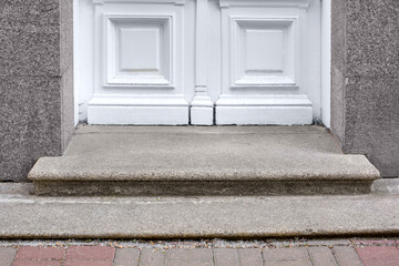 granite threshold at the entrance door made of white wood and gray facade cladding of an old retro...