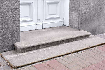 granite threshold at the entrance door made of white wood and gray facade cladding of an old retro...