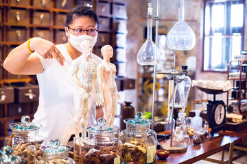 The doctor of traditional medicine is presenting the properties of the herbs with blurry dried herbs on vintage balance scale at old medicine herbs shop. Ancient Herbs Research Laboratory.