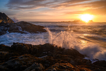Fototapeta na wymiar Wavy sea against the rocky seashore in Tofino, Vancouver Island, Canada at sunset