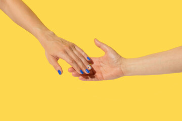 Female hands gently touching each other on yellow background. Minimal concept.