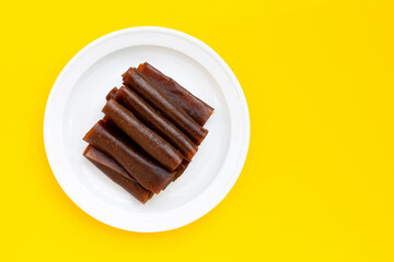 Dried mango paste in white plate on yellow background.