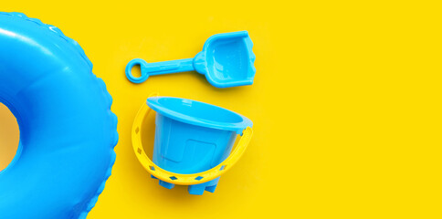 Plastic toys, Swimming pool ring with bucket and shovel for sand on yellow surface. © Bowonpat