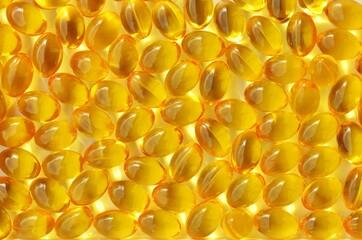 Vitamin D capsules close-up as a yellow background on a full frame