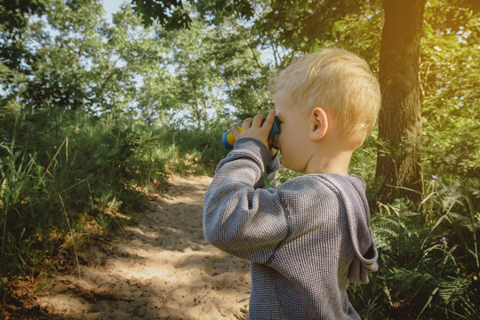 Young boy hiking and bird watching on a trail with binoculars at Indiana Dunes State Park