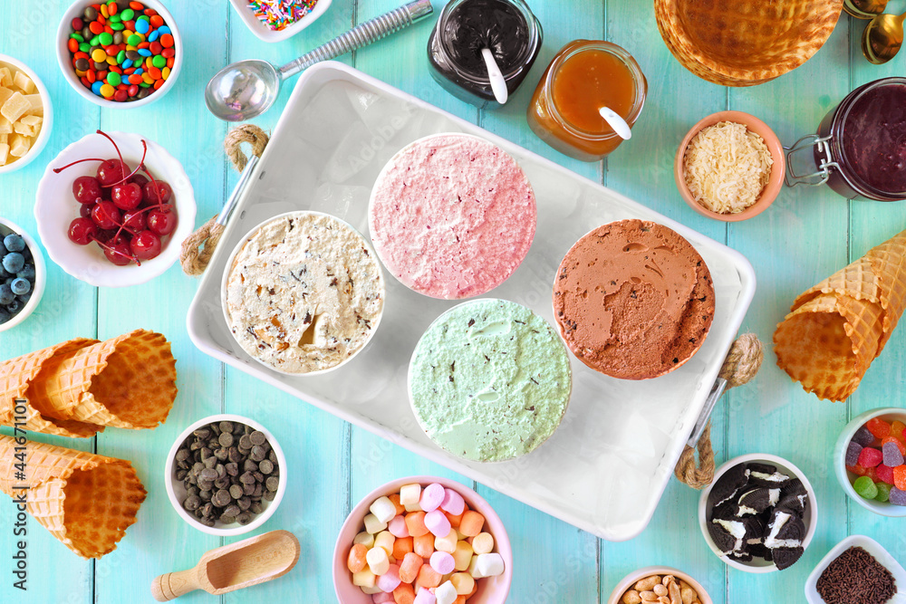 Poster summer ice cream buffet with different flavors and sweet toppings. top view table scene on a blue wo