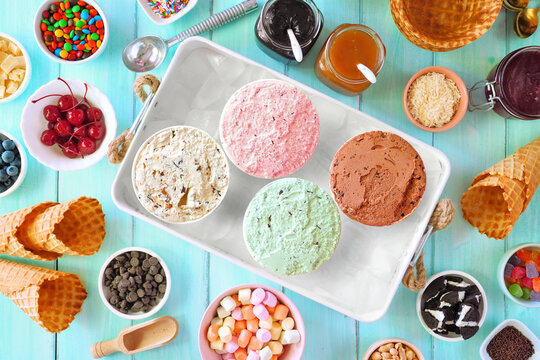 Summer ice cream buffet with different flavors and sweet toppings. Top view table scene on a blue wood background.