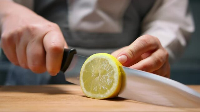 Female hands cut juicy lemon in round slices. Close up