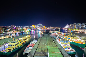 Panoramic night view of Sydney Harbour and City Skyline of circular quay the bridge  nsw Australia.  bright neon lights reflecting off the water