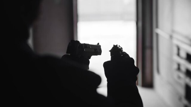 A silhouette of man holding two guns in his hands