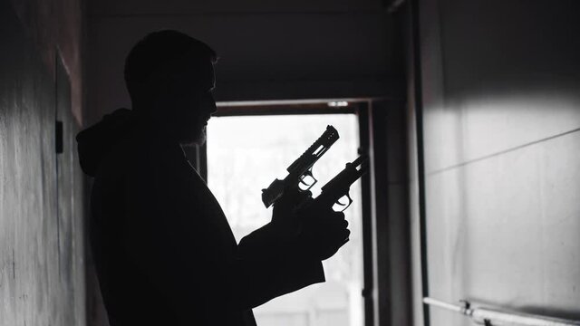 A silhouette of man holding two guns and aiming