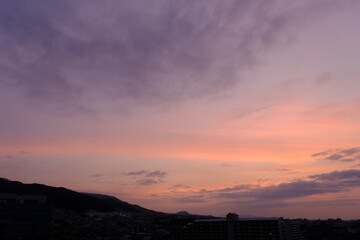 神戸市東灘区のマンション上層階から明け方の六甲山系。東の空から太陽が昇り空と雲がオレンジ色に染まる。六甲山と甲山の上雲の雲が美しい