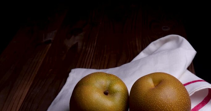 梨が2つ布の上にあるティルトダウン動画、黒背景