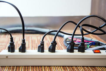 Old and damaged electric adapter power plug has many appliances are plugged outlet socket concept of risk danger overloaded current electrical.