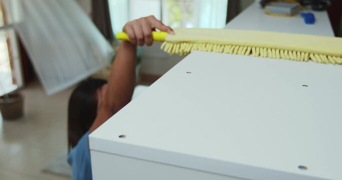 Woman cleaning the cabinet with microfiber cloth duster