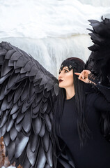 fantasy fairy-tale photo of a beautiful young woman in a black angel costume in winter