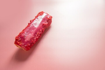 red strawberry or raspberry eclair on a rose background close-up