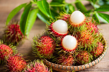 Fresh and ripe rambutan sweet tropical fruit peeled rambutan with leaves, Rambutan fruit on basket and wooden background harvest from the garden